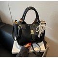 Vue détaillée du sac seau en cuir noir avec fermoir doré et breloque perle et dentelle - Noir avec pendentif