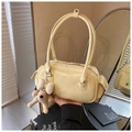 Détail du sac à main jaune crème en cuir verni avec de longues anses et pendentif chien - Avec Pendentif en Peluche / Jaune