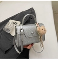 Detail view of silver textured crossbody bag with plush bear charm and woven rope décor - Silver (With Pendant)