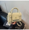 Gros plan du petit sac carré crème en similicuir avec détails de logo doré - Vert
