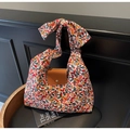 Bloemen canvas draagtas met lederen flap en grote strik schouderband op een stoel - Oranje Bloemenstijl