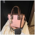 Close-up of pink oil wax leather bucket bag with dark brown handles and charms - Pink