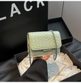 Dettaglio della borsa a tracolla intrecciata verde con catena argento su sfondo design - Verde