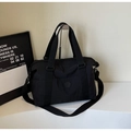 Close-up of durable black nylon travel tote featuring a round logo and adjustable strap - Black