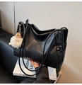Detail of black leather tote bag featuring letter embossing and a plush monster charm - Black With Pendant