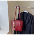 Détail du sac seau bordeaux en cuir verni avec pompon sur un blazer noir élégant - Avec Pendentif / Rouge Ankara