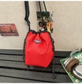 Détail d'un sac seau à carreaux rouges avec cordons noirs et étiquette sur toile canvas - Rouge