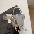 Chic light blue bucket bag with gold metal hardware and tennis racket charm detail - Light Blue With Pendant