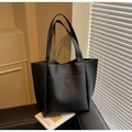 Detalle de bolso tote grande negro con textura mate sobre un sofá de cuero - Negro