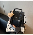 Detail of black patent leather bag with twin strap buckles and decorative bear charm - With Charm / Black