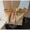Detail of handwoven straw tote bag featuring brown leather straps and mesh texture - Brown