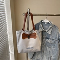 Light gray canvas tote bag with brown leather handles and decorative bone zipper patch - Grey Without Pendant