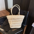 Elegante borsa tote in paglia intrecciata beige con nappa su una sedia di pelle nera - Bianco Sporco