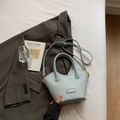 Mint green woven bucket bag with top handles and adjustable strap in lifestyle setting - No Pendant / Light Blue