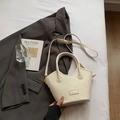 Cream white woven bucket bag with top handle and adjustable strap in a lifestyle setting - No Pendant / Off White