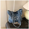 Detail van blauwe denim draagtas met vintage wassing en applicaties van gerafelde strikken - Blauw