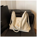 Detail view of cream white leather tote bag with star patch and drawstring closure - White