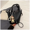 Détail d'un sac seau en cuir noir grainé avec breloque perle sur un blazer gris - Noir avec pendentif