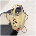 Détail d'un sac seau beige en cuir grainé avec breloque perle sur fond décoratif - Jaune avec Pendentif