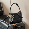 Schwarze glänzende Eimer-Handtasche aus Leder mit Perlen-Schleifen-Anhänger und Riemen - Mit Schleifenanhänger / Schwarz
