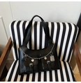 Detalle de bolso negro de cuero con cadenas de plata, colgantes de corazón y bolsillos dobles - Negro