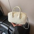 Chic off-white bowling bag with CLEARCK logo and silver chain strap held by hand - White