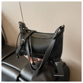 Detalle de bolso bandolera negro con diseño plisado y accesorios metálicos plateados - Negro