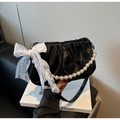 Detail of black pleated satin handbag featuring large faux pearl strap and lace bow accent - Black