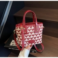 Detail of red heart jacquard pattern on a tote bag with elegant gold hardware and leather trim - Heart