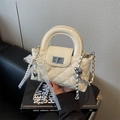 Quilted cream patent leather handbag with pearl chain and bow detail in a handheld view - With Charm / Off White
