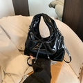 Glänzende schwarze Lackleder-Handtasche mit Schleife und abnehmbarem Gurt auf Stuhl - Schwarz