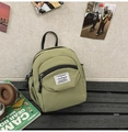 Close-up of light green shell-shaped crossbody bag with brand label on a wooden bench - Green