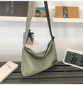 Detail of sage green nylon half-moon tote bag with black logo patch and adjustable strap - Green