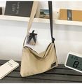Close-up of beige tote bag with black adjustable strap and industrial brand label - Light Khaki