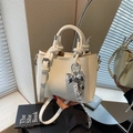 Sac seau beige chic avec poignée nouée, texture litchi et pendentif nœud argenté - Beige Avec Charme