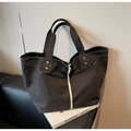 Detailed view of black canvas tote bag with white strap and brass rivet reinforcements - Black
