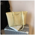 Detail der Webstruktur und des Metalllogos auf einer blassgelben Kunstleder-Tote-Bag - Gelb