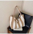Detail of a large striped canvas tote bag resting on a leather chair in a home setting - Wide Stripe Khaki