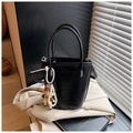 Detalle de bolso tipo cubo negro con colgante de perlas sobre fondo de americana beige - Negro (Con Colgante de Muñeca) / Negro con colgante