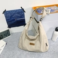 Detailansicht der cremefarbenen Nylontasche mit Markenlogo aus Leder und Trageriemen - Weiß