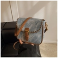 Detail der hellblauen Denim-Satteltasche mit braunen Lederflechtkanten und Metallschnalle - Blau