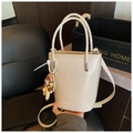 Bolso cubo de cuero blanco crema con asas, logo de moda y un lindo colgante de muñeca - Beige (Con Colgante de Muñeca) / Beige Con Amuleto