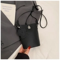 Close-up of black lychee grain bucket bag featuring a silver buckle and cute dog charm - Black