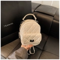Close-up of beige quilted leather mini backpack with metal chain and silver turn-lock - White
