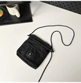 Detail of black nylon crossbody bag with mesh pocket and logo on white surface - Black