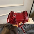 Burgundy faux leather dumpling bag with chunky chain and adjustable strap in hand - Red