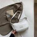 Sac bandoulière demi-lune blanc texture litchi avec bandoulière réglable sur lit blanc - Blanc Sans Pendentif