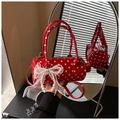 Close-up of red polka dot cylinder bag with pearl bow and lace detail shown in a mirror - With Charm Style / Red with Pendant