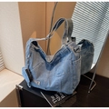 Macro detail of washed denim tote bag showing functional front pocket and small round coin purse - Blue