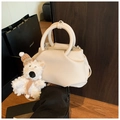 Detail of cream pleated leather bucket bag with plush bear charm on wooden surface - With Charm / White